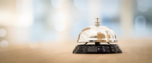 Service bell on wooden counter, blurred background.
