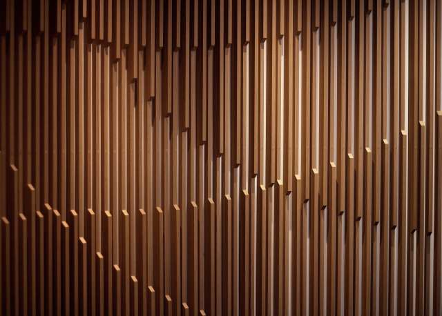 Wooden slat wall with varying depth and shadows.